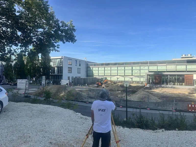 Vermesser mit Totalstation vor der Baustelle am Ostalb-Klinikum Aalen