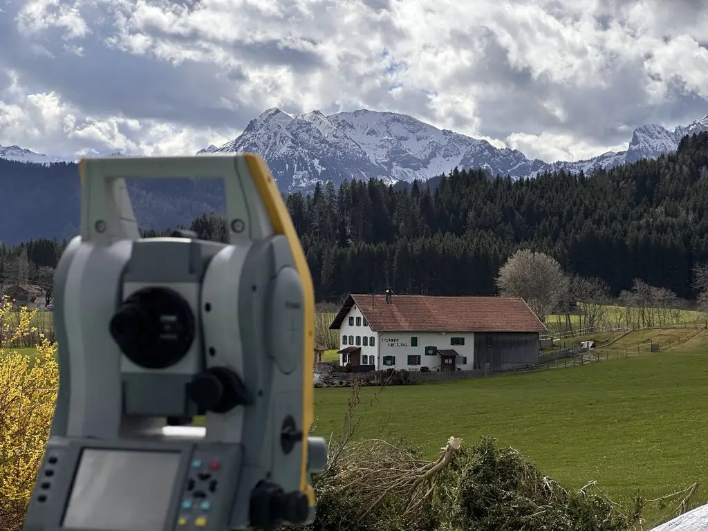 Totalstation bei einer Vermessung vor Alpenpanorama im Allgäu