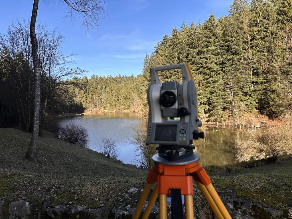 Totalstation bei einer Geländeaufnahme an einem See